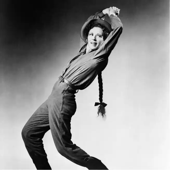 Black and white photo of Agnes de Mile dressed as a cowboy and leaning backwards, as if in the middle of a dance.
